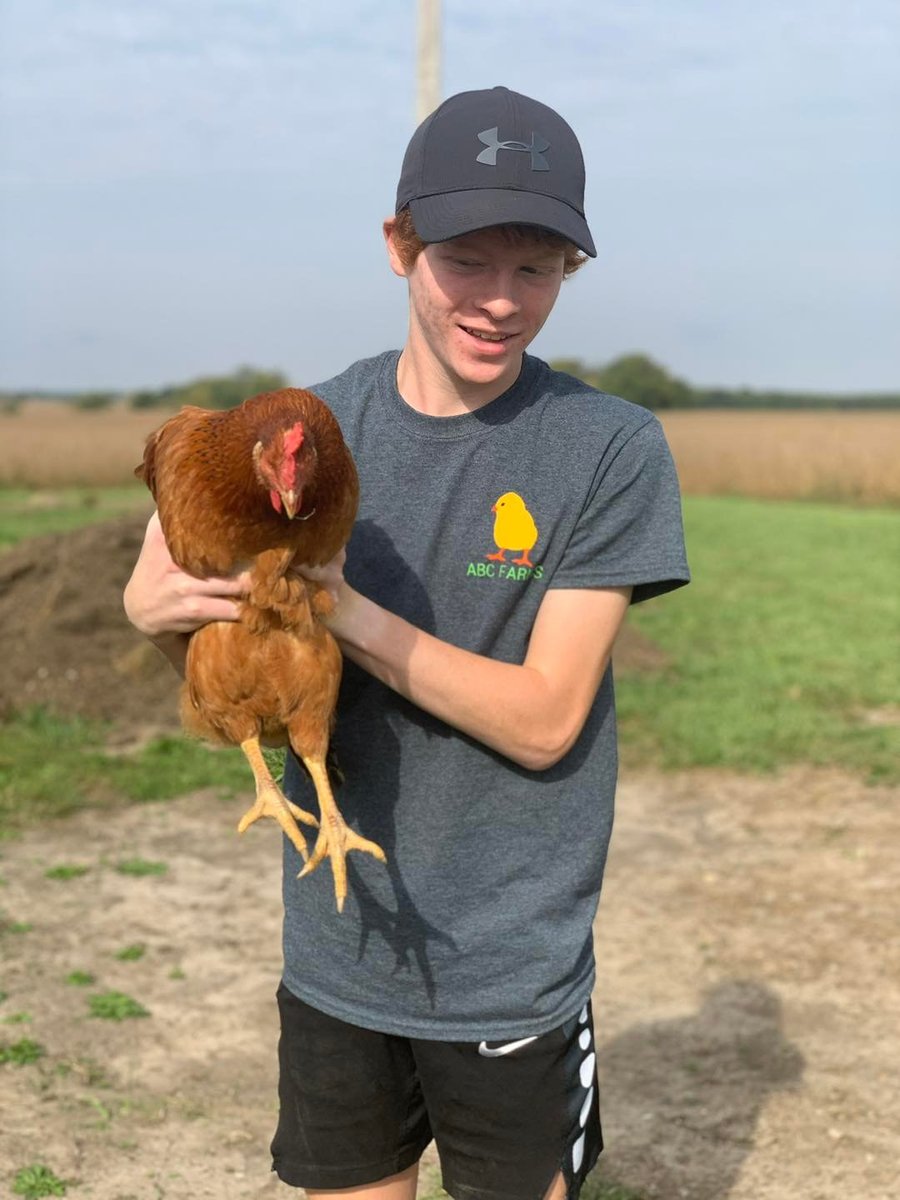One of the kids holding a chicken, wearing the ABC Farms shirt