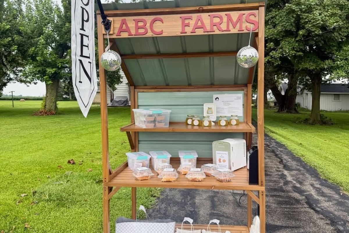 The ABC Farms village stand, a wooden cart with shelves of honey jars and packaged treats